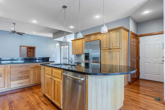 11370 Crottinger Rd, Plain City, OH 43064 - kitchen featuring appliances with stainless steel finishes, a sink, dark countertops, a kitchen island with sink, and light wood finished floors