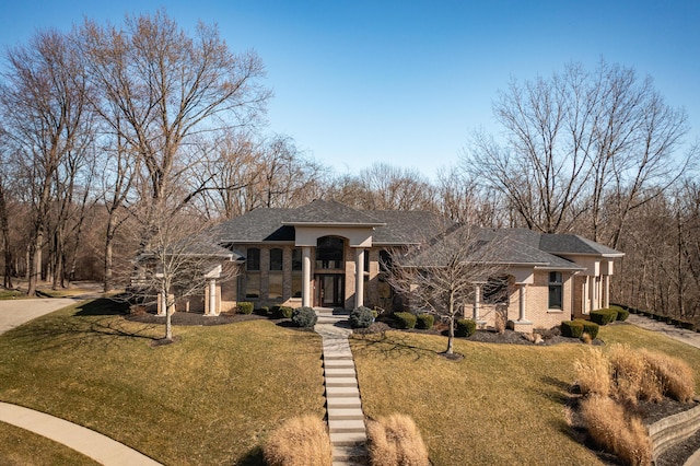 view of front facade featuring driveway, brick siding, and a front lawn