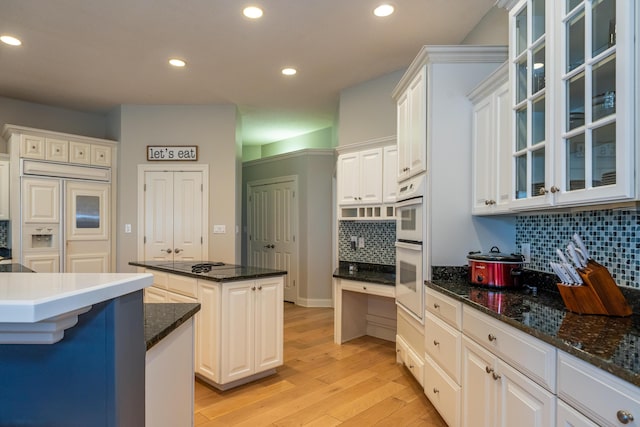 kitchen featuring light wood-style flooring, recessed lighting, decorative backsplash, glass insert cabinets, and a center island