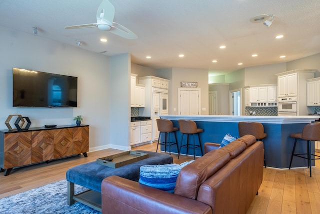 living room featuring recessed lighting, baseboards, and light wood-style floors