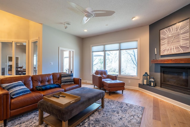 living room with hardwood / wood-style floors, a glass covered fireplace, baseboards, and a textured ceiling