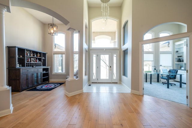 entrance foyer featuring wood finished floors, arched walkways, and ornate columns