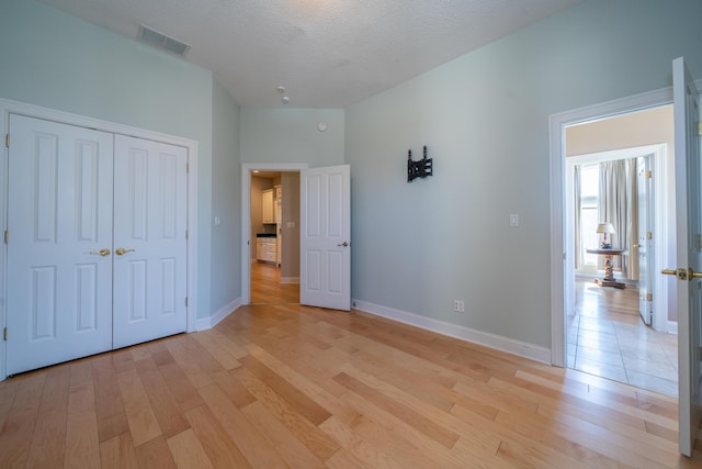 unfurnished bedroom with visible vents, baseboards, a textured ceiling, and light wood-style flooring