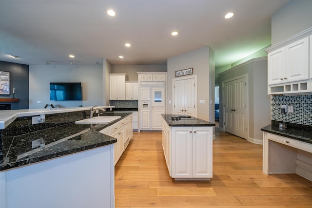 kitchen with a sink, white cabinets, light wood finished floors, and a center island