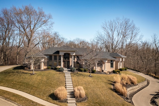 view of front of home featuring a front yard, brick siding, driveway, and roof with shingles