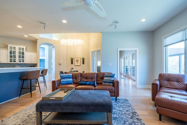 living room with recessed lighting, arched walkways, light wood-type flooring, and ceiling fan