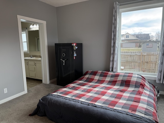 carpeted bedroom featuring connected bathroom and sink