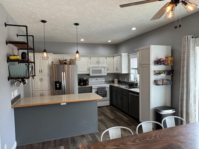 kitchen with sink, dark wood-type flooring, stainless steel appliances, white cabinets, and decorative light fixtures