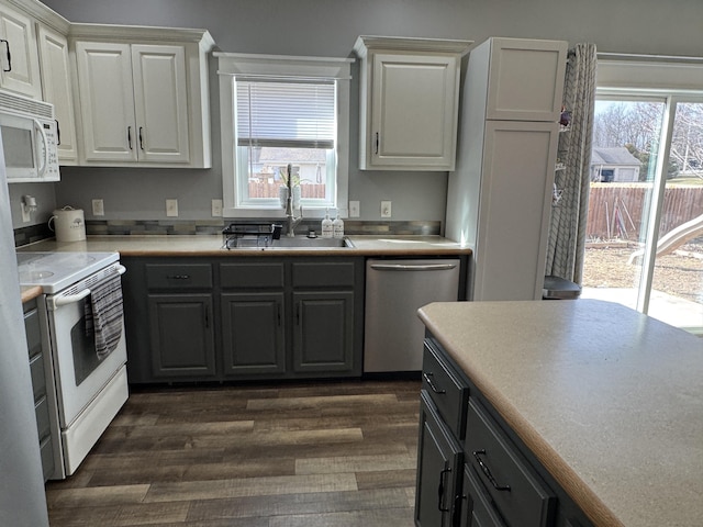 kitchen featuring white cabinetry, dark hardwood / wood-style flooring, sink, and white appliances