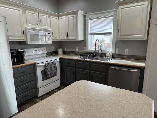 kitchen with white cabinetry, sink, white appliances, and dark hardwood / wood-style floors