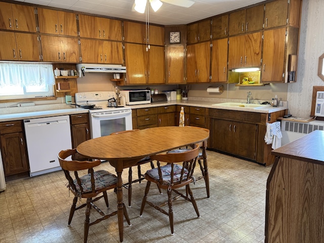 210 E Second St, Rockford, OH 45882 - kitchen with white appliances, light flooring, under cabinet range hood, brown cabinetry, and radiator heating unit