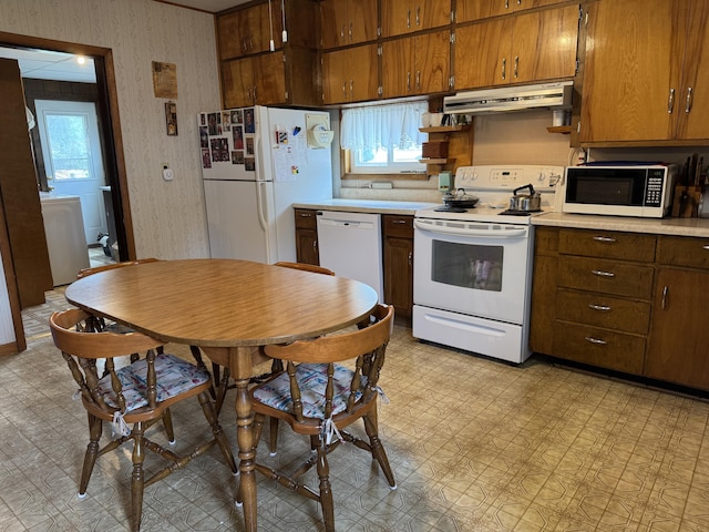 210 E Second St, Rockford, OH 45882 - kitchen with white appliances, under cabinet range hood, wallpapered walls, light countertops, and washer / dryer