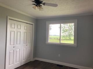 4173 Navajo Trl, Jamestown, OH 45335 - unfurnished bedroom featuring ornamental molding, a closet, dark wood-style flooring, and ceiling fan