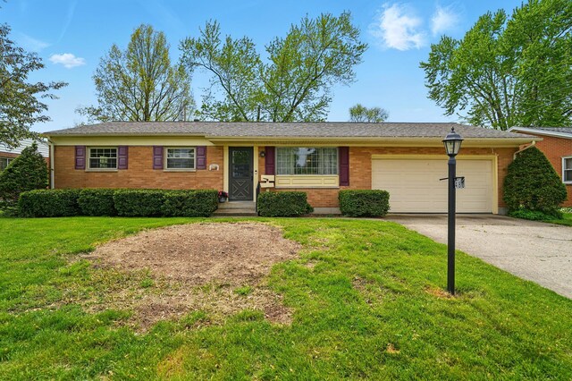 single story home with brick siding, a garage, a front lawn, and concrete driveway