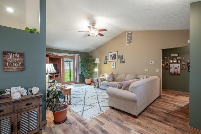 living room with vaulted ceiling, hardwood / wood-style floors, a textured ceiling, and ceiling fan