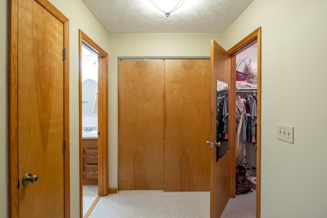 hallway featuring sink, light carpet, and a textured ceiling