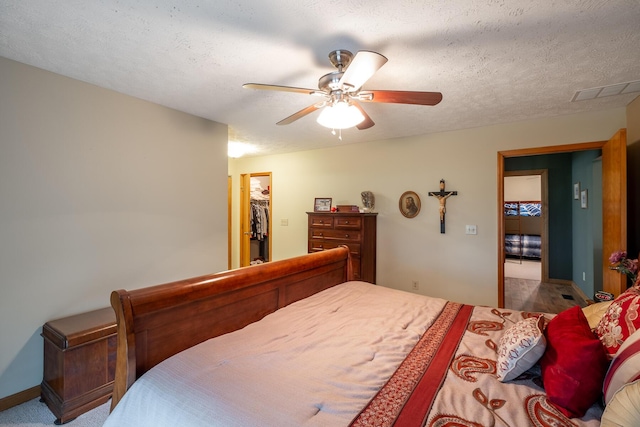 bedroom featuring ceiling fan, a spacious closet, a closet, and a textured ceiling