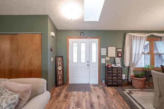 foyer with wood-type flooring, a textured ceiling, and a skylight