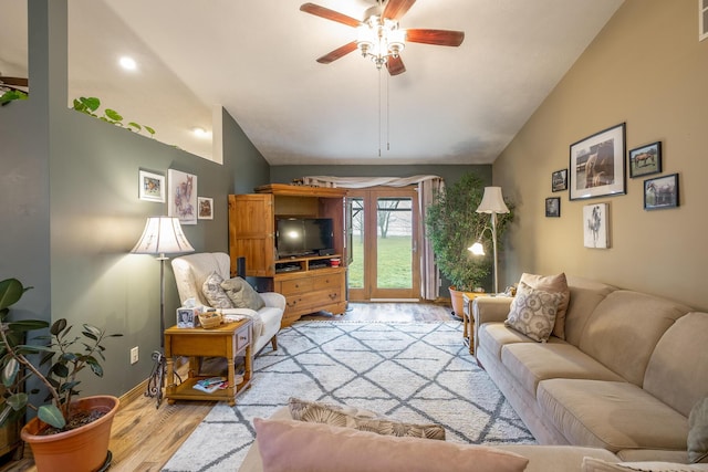 living room with lofted ceiling, ceiling fan, and light hardwood / wood-style flooring