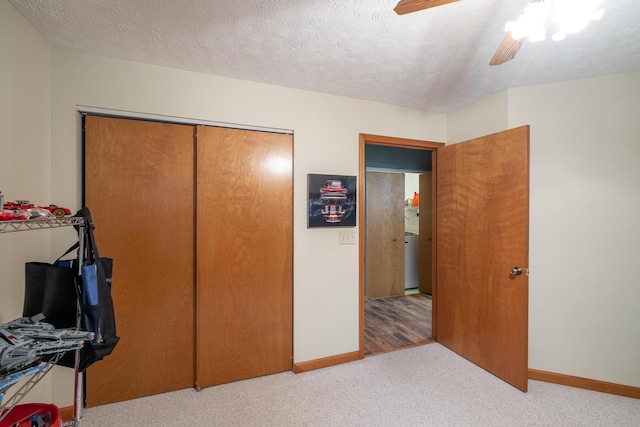 bedroom with washer / clothes dryer, ceiling fan, light carpet, a textured ceiling, and a closet