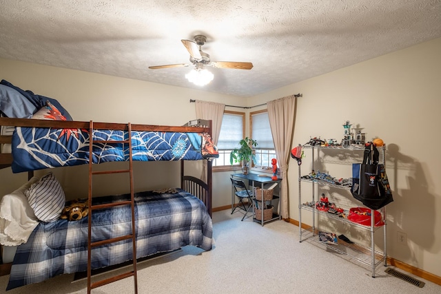 carpeted bedroom featuring ceiling fan and a textured ceiling