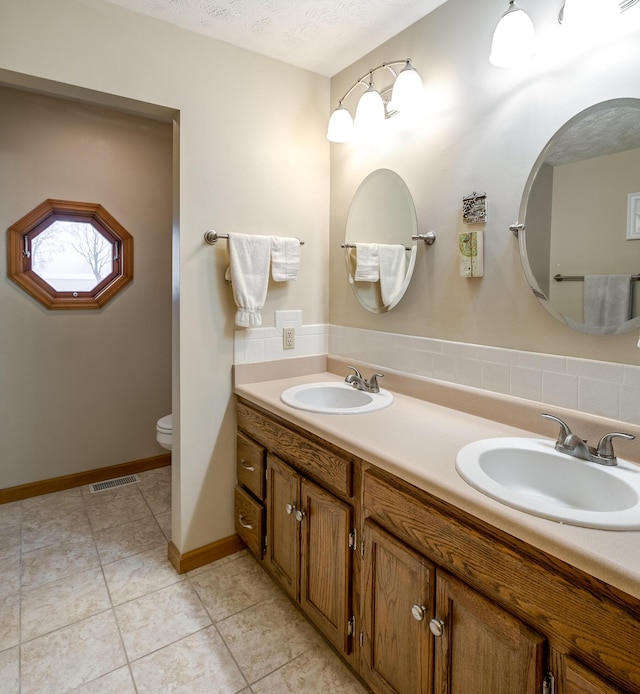 bathroom featuring vanity, tile patterned floors, toilet, and a textured ceiling