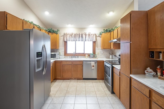 kitchen featuring sink, light tile patterned floors, appliances with stainless steel finishes, decorative backsplash, and vaulted ceiling