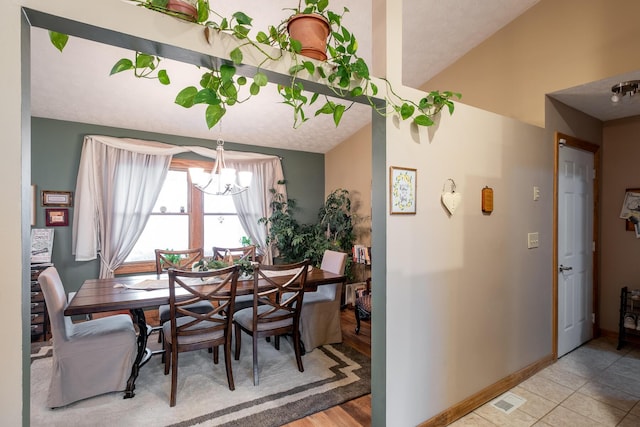 tiled dining space featuring lofted ceiling and a notable chandelier