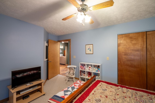 bedroom featuring ceiling fan, a closet, carpet, and a textured ceiling