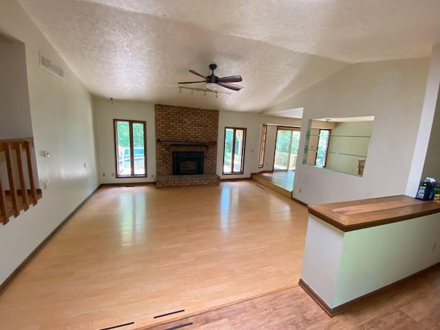 2700 Myeerah Trl, West Liberty, OH 43357 - unfurnished living room featuring a ceiling fan, light wood-type flooring, a textured ceiling, a fireplace, and vaulted ceiling