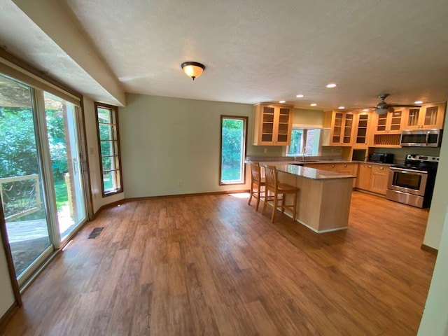 2700 Myeerah Trl, West Liberty, OH 43357 - kitchen featuring appliances with stainless steel finishes, glass insert cabinets, a kitchen breakfast bar, wood finished floors, and baseboards