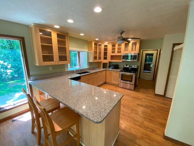 2700 Myeerah Trl, West Liberty, OH 43357 - kitchen with appliances with stainless steel finishes, a sink, a peninsula, glass insert cabinets, and light wood-style flooring