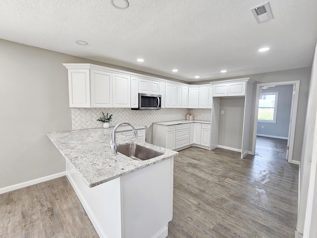 5412 Lock Two Rd, New Bremen, OH 45869 - kitchen with visible vents, a sink, stainless steel microwave, a peninsula, and light wood-style floors