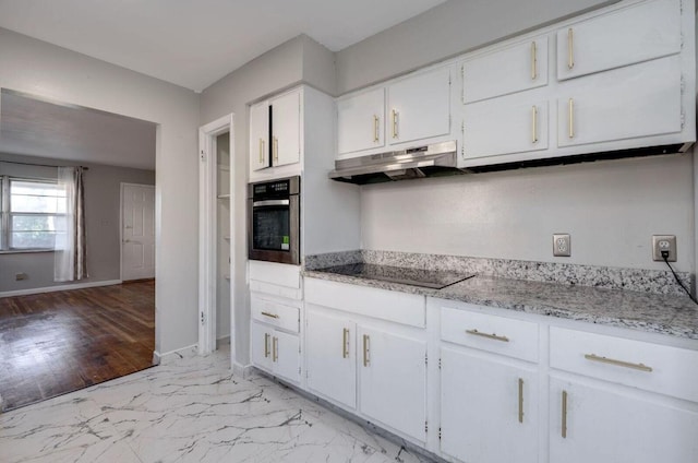 kitchen featuring black electric stovetop, white cabinetry, oven, under cabinet range hood, and baseboards