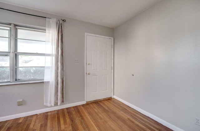 spare room with baseboards and wood finished floors