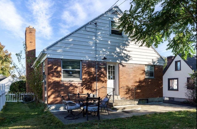 back of property with a patio, a chimney, fence, a yard, and brick siding