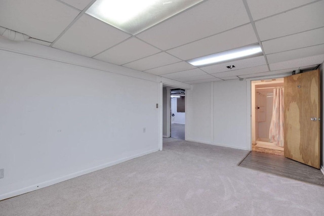 carpeted empty room with a drop ceiling and baseboards