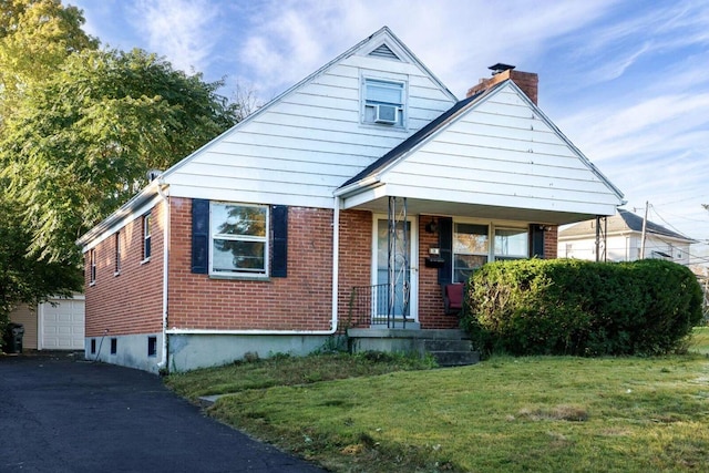 bungalow-style home featuring a garage, an outbuilding, covered porch, a front lawn, and brick siding