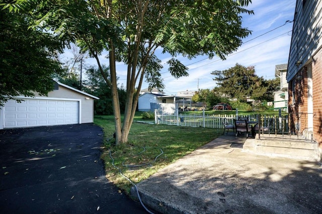 view of yard featuring a garage, fence, and an outbuilding