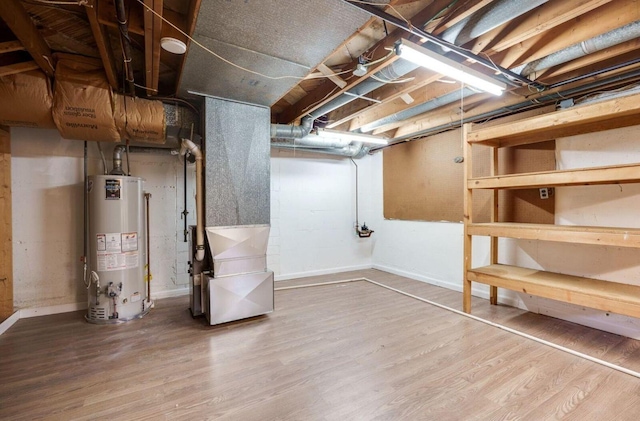 unfinished basement featuring baseboards, water heater, heating unit, and wood finished floors