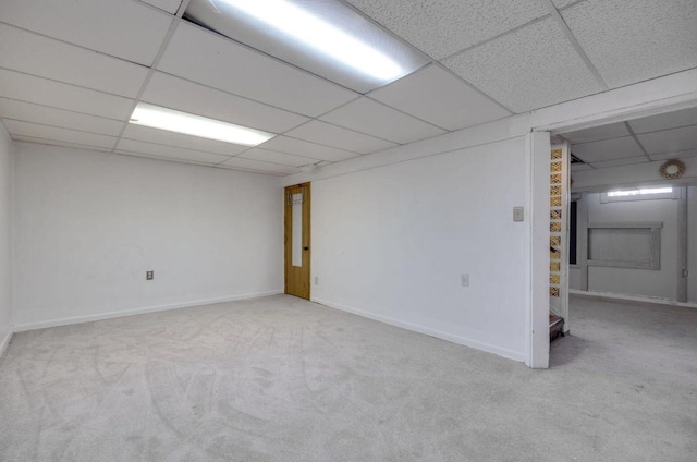 finished basement with a paneled ceiling, baseboards, and carpet flooring