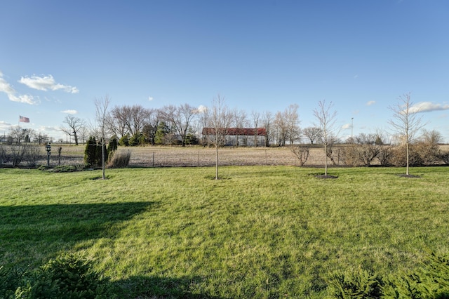 view of yard with fence and a rural view