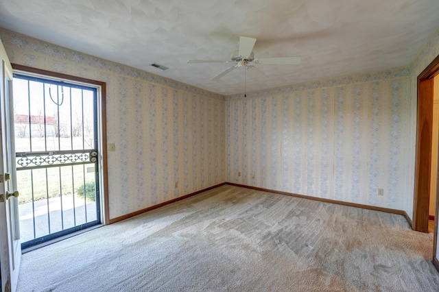 spare room featuring baseboards, wallpapered walls, visible vents, and ceiling fan
