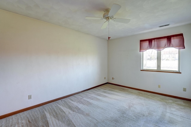 empty room with baseboards, ceiling fan, visible vents, and carpet