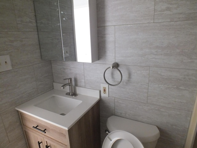 bathroom featuring vanity, tasteful backsplash, tile walls, and toilet