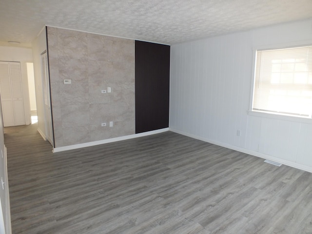 unfurnished room featuring wood-type flooring and a textured ceiling