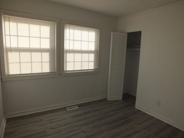 unfurnished bedroom featuring dark wood-type flooring and a closet