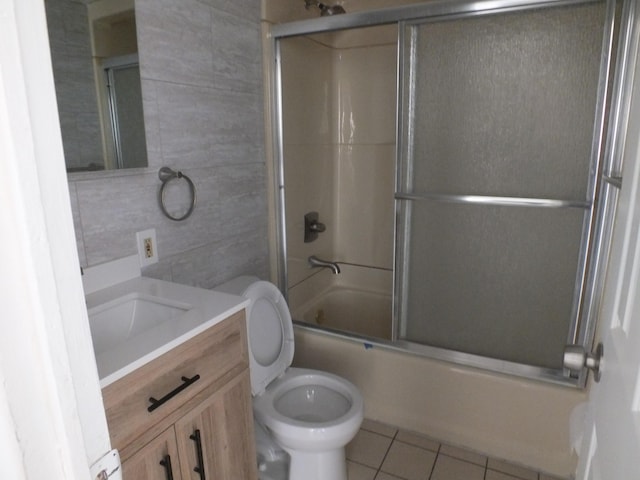 full bathroom featuring enclosed tub / shower combo, tile walls, vanity, tile patterned floors, and toilet