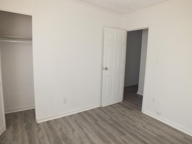 unfurnished bedroom with crown molding, dark hardwood / wood-style floors, and a closet