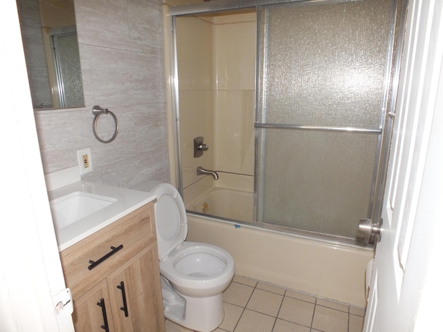 full bathroom with tile walls, shower / bath combination with glass door, vanity, toilet, and tile patterned floors